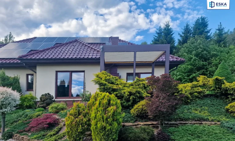 Pergola bioklimatyczna z brązową ramą i kremowymi lamelami przy parterowym domu w Jaworzu